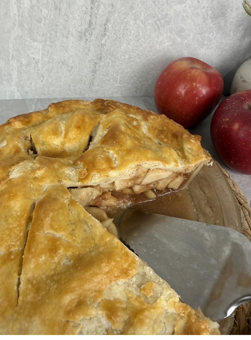 A slice of apple pie lifted to show the spiced filling inside