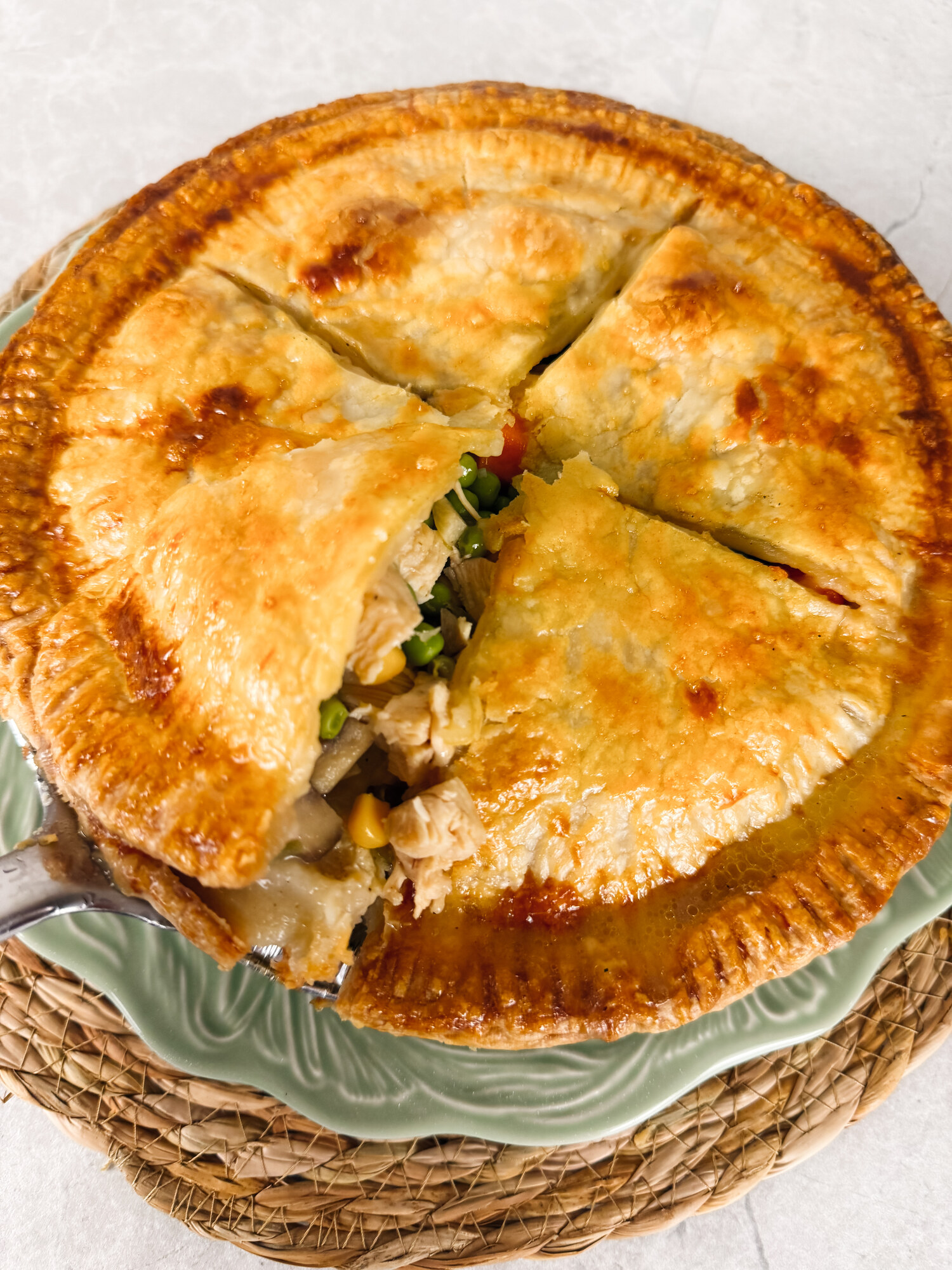 A chicken potpie cut open to show the creamy filling of chicken, peas, corn, and carrots