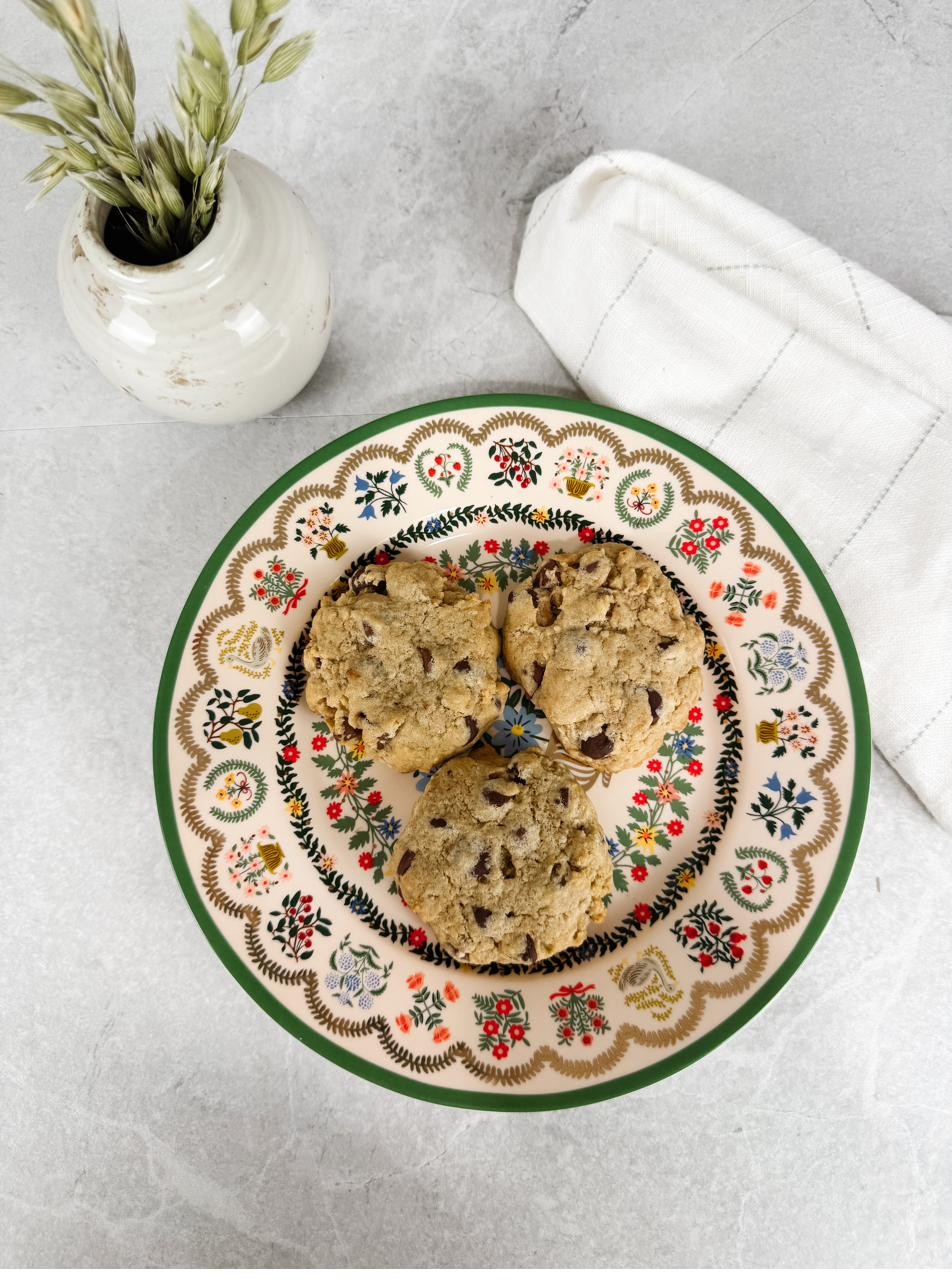 Chocolate chip cookies on a floral plate beside a linen napkin