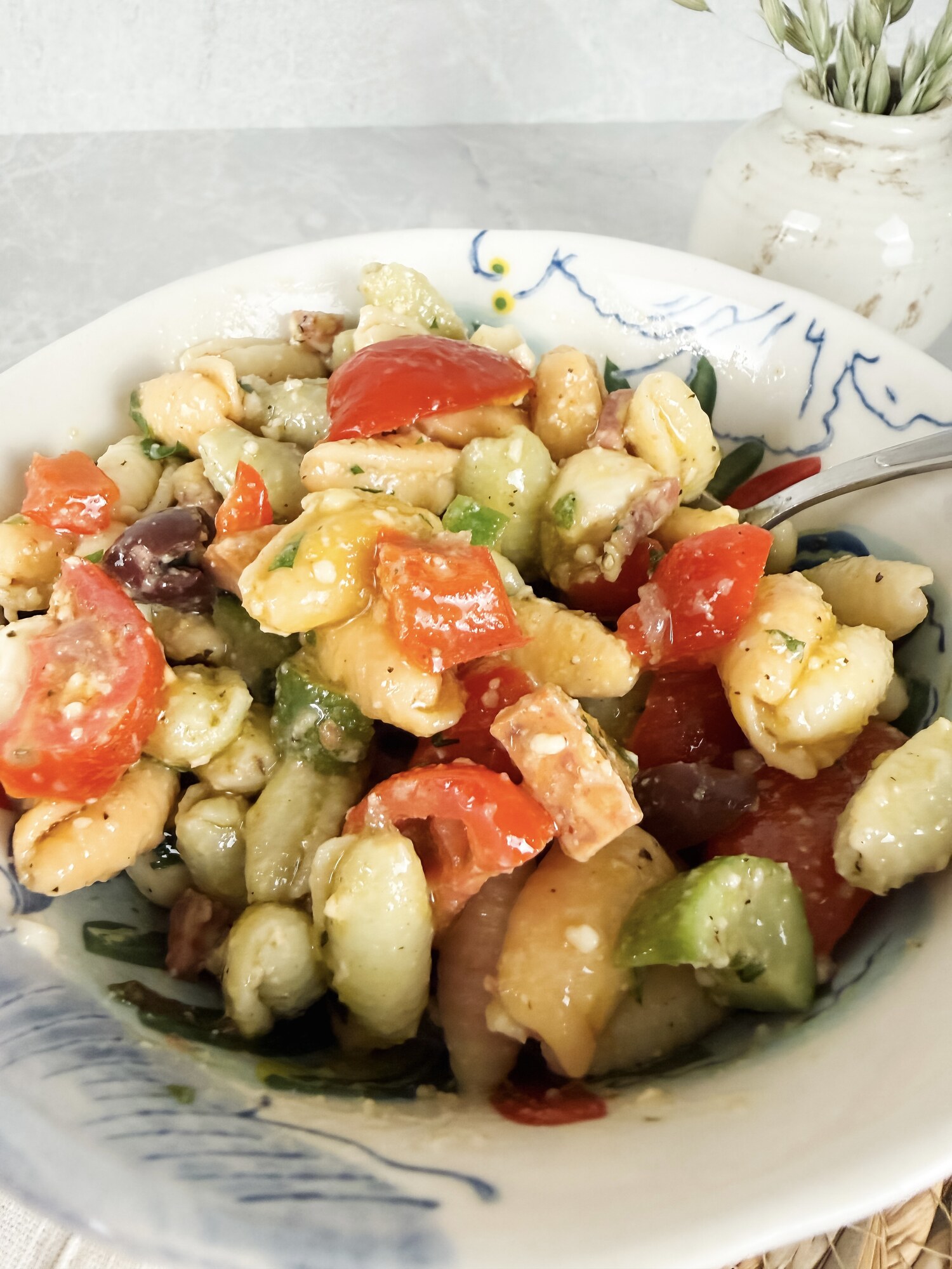 A close view of the antipasto pasta salad with tomatoes, peppers, olives, salami, and herbs