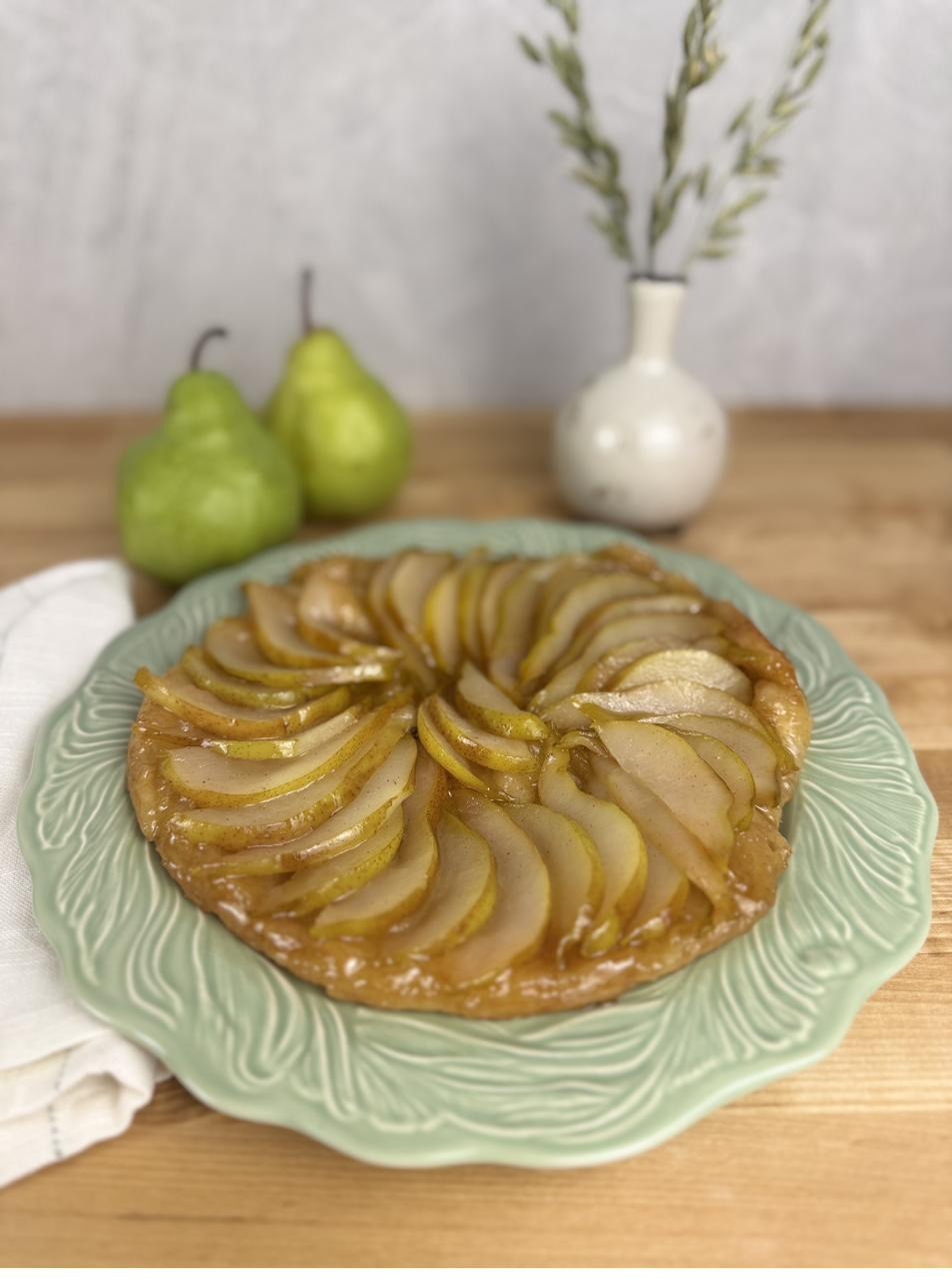 A pear tarte tatin on a pale green plate, pears arranged in a ring with caramel