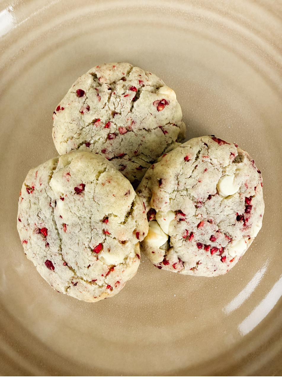Raspberry white chocolate cookies seen from above on a tan plate