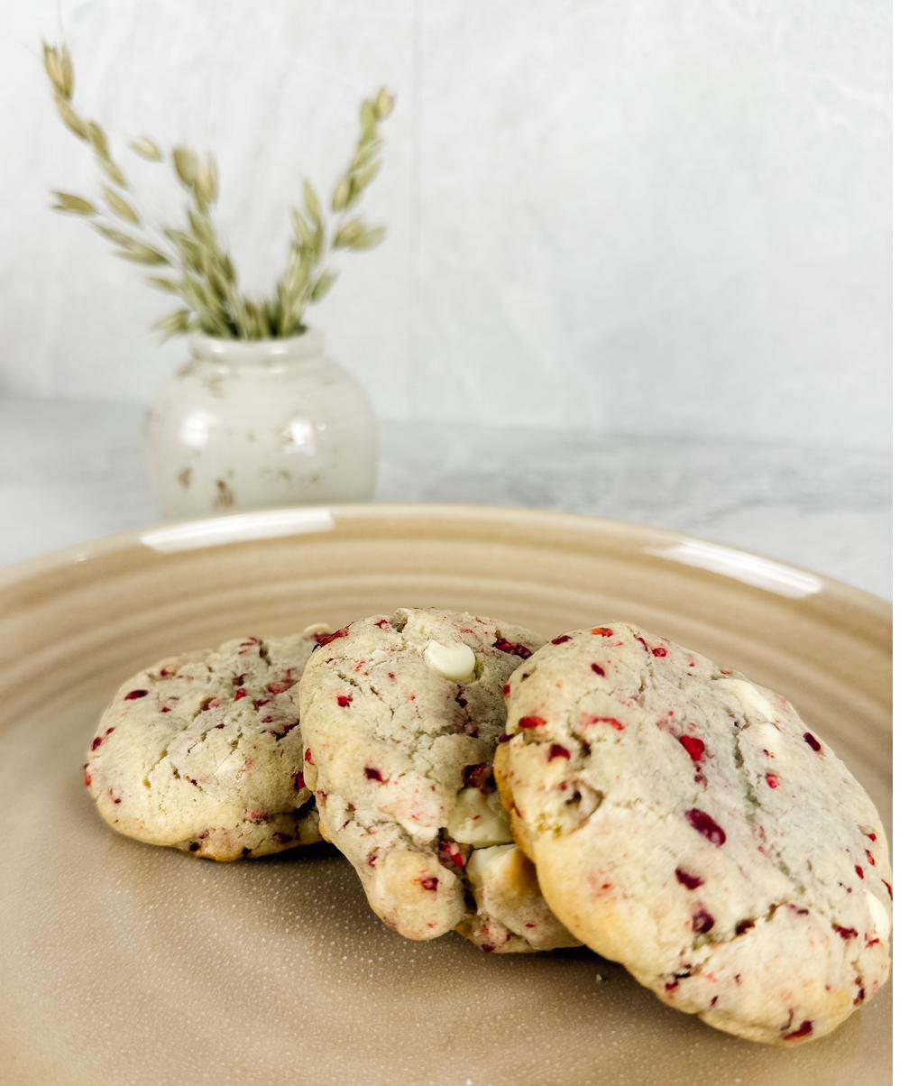 Three raspberry white chocolate cookies on a tan stoneware plate