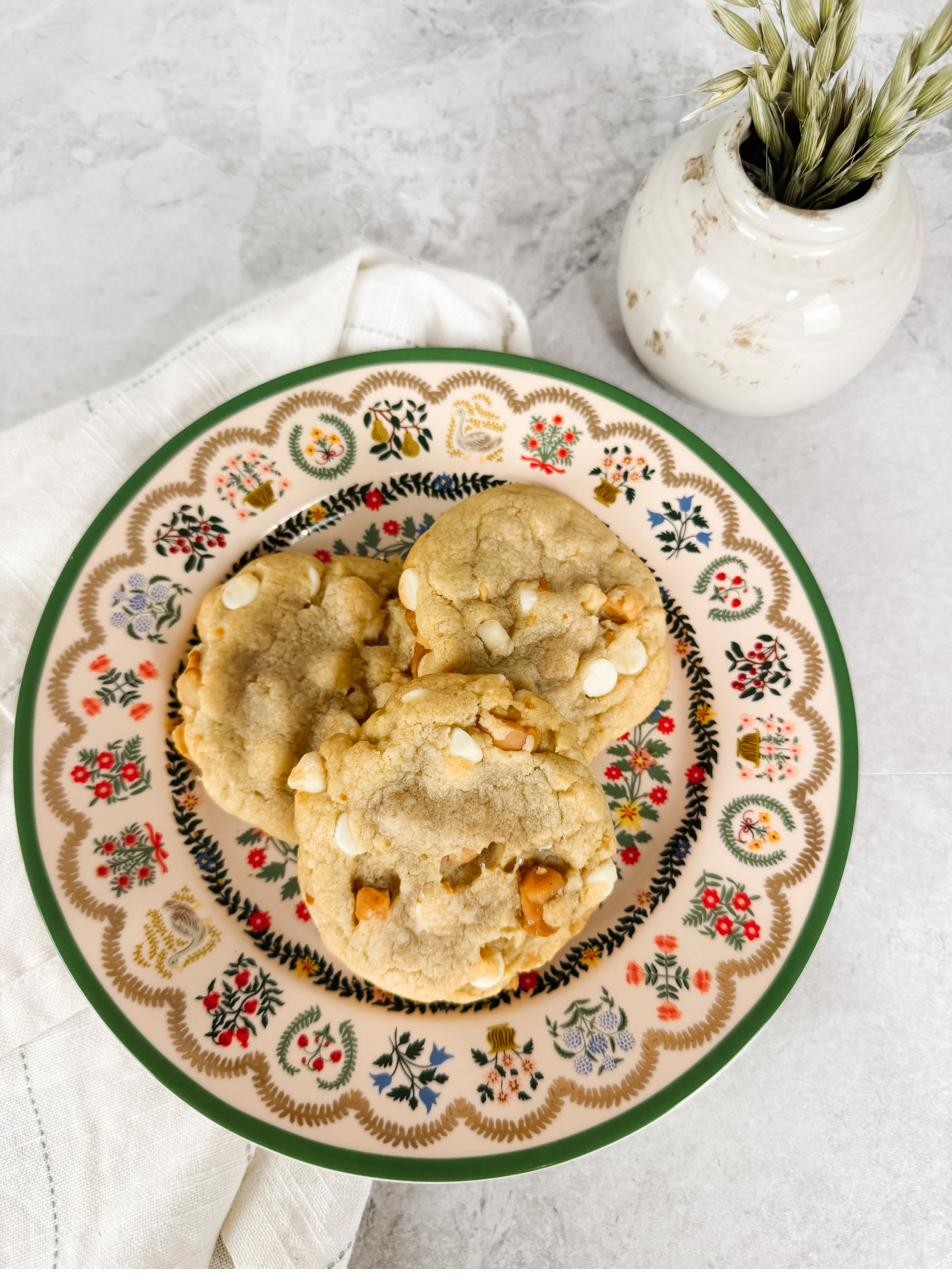 White chocolate macadamia cookies on a floral-rimmed plate, seen from above